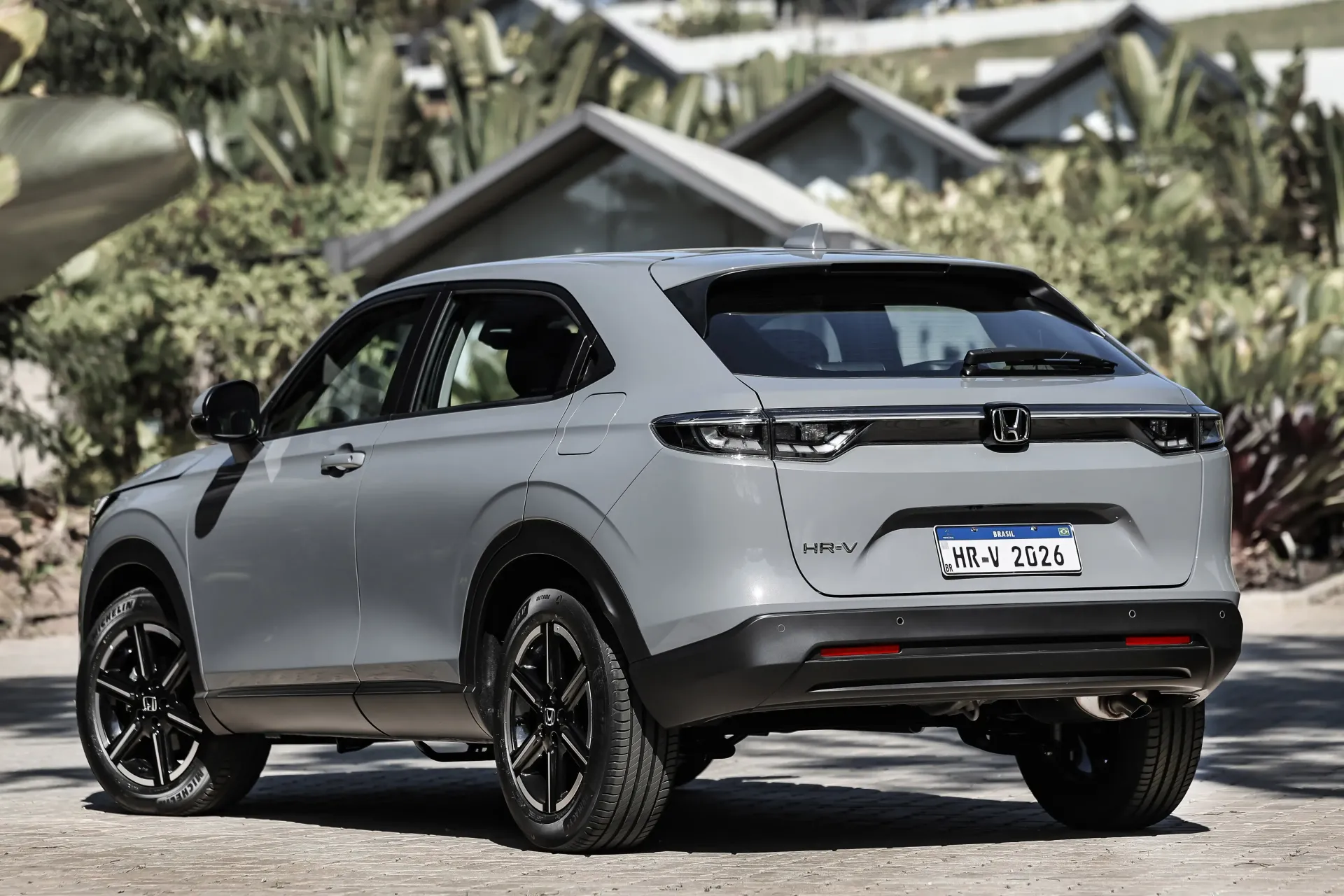 Gray compact SUV parked outdoors on a gravel driveway, rear three-quarter view