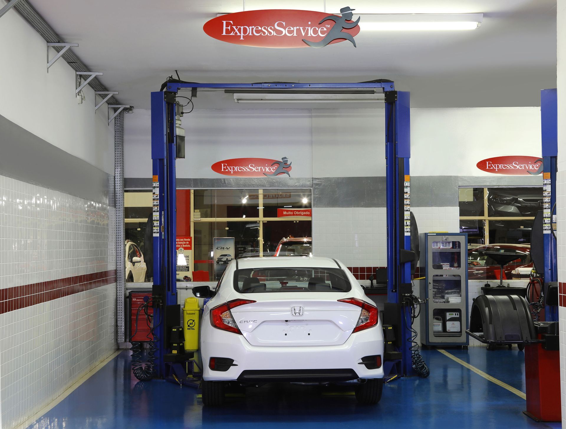 Um honda civic branco está no elevador de uma garagem