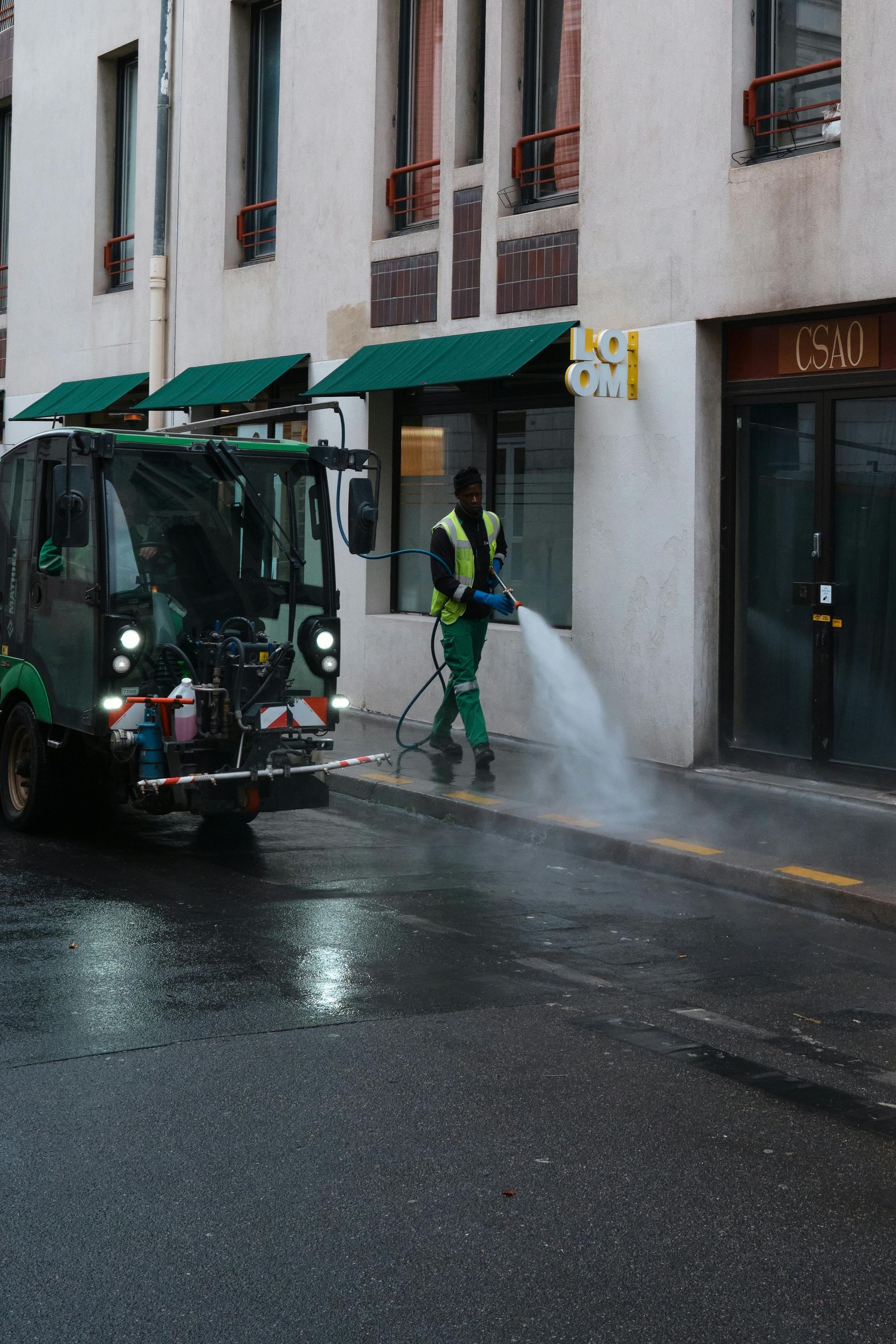 A man is using a high pressure washer to clean a sidewalk.