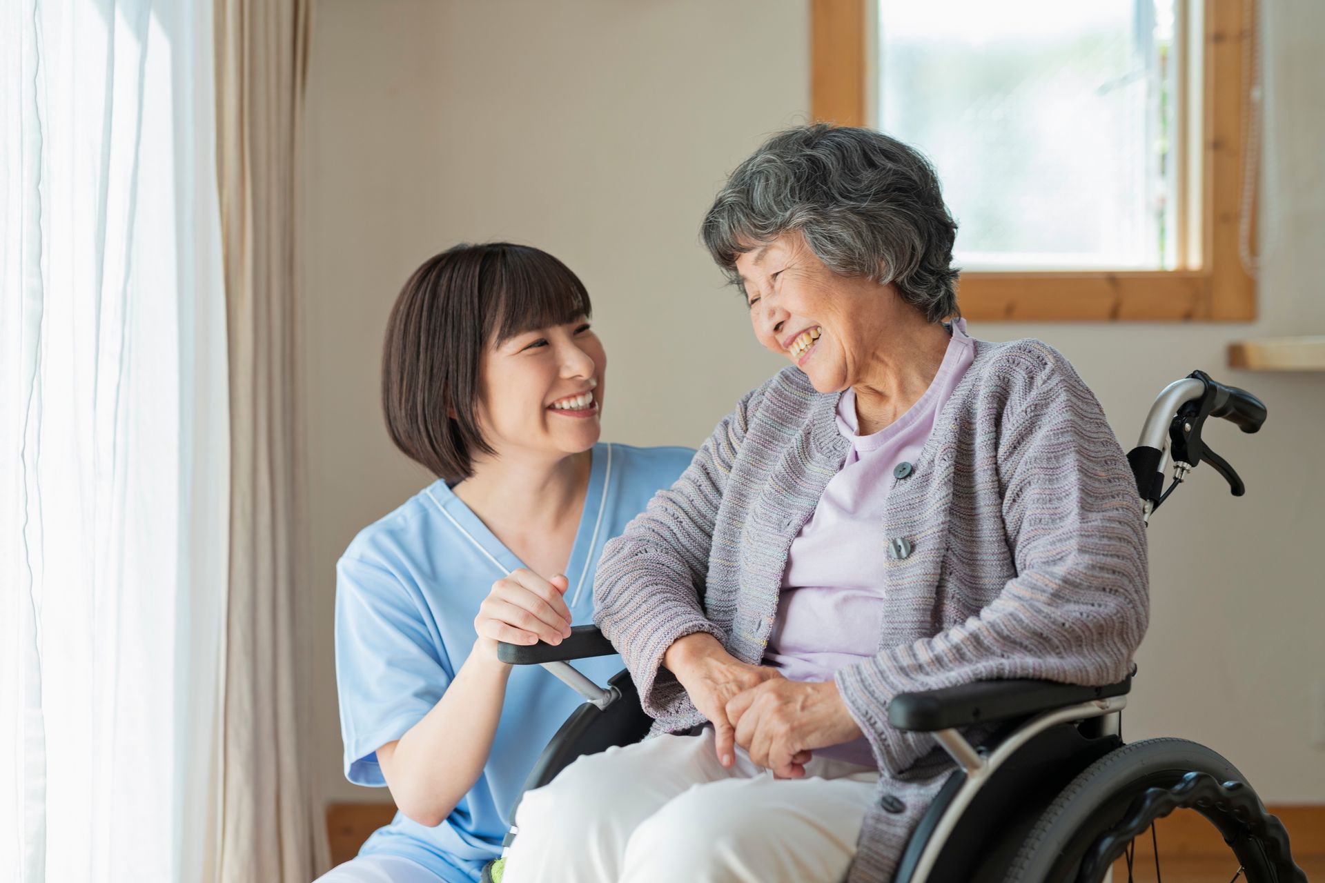 A nurse is talking to an elderly woman in a wheelchair.