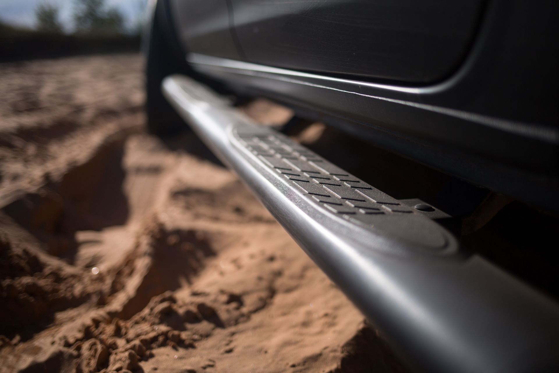 A close up of a car 's side step in the sand.