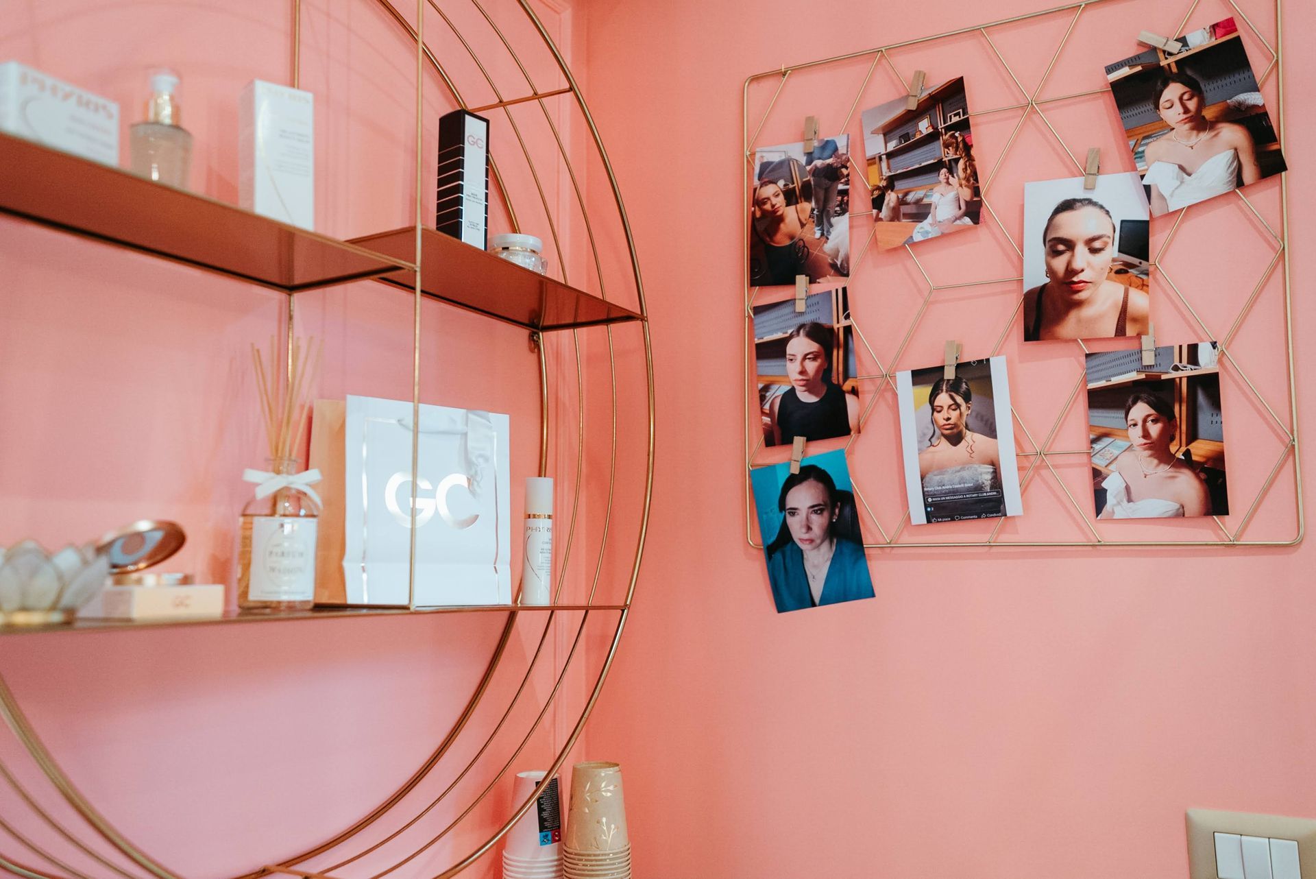 Spazio dedicato alla bellezza con pareti rosa e ripiani circolari dorati che ospitano prodotti e foto fissati su una griglia a forma di diamante.