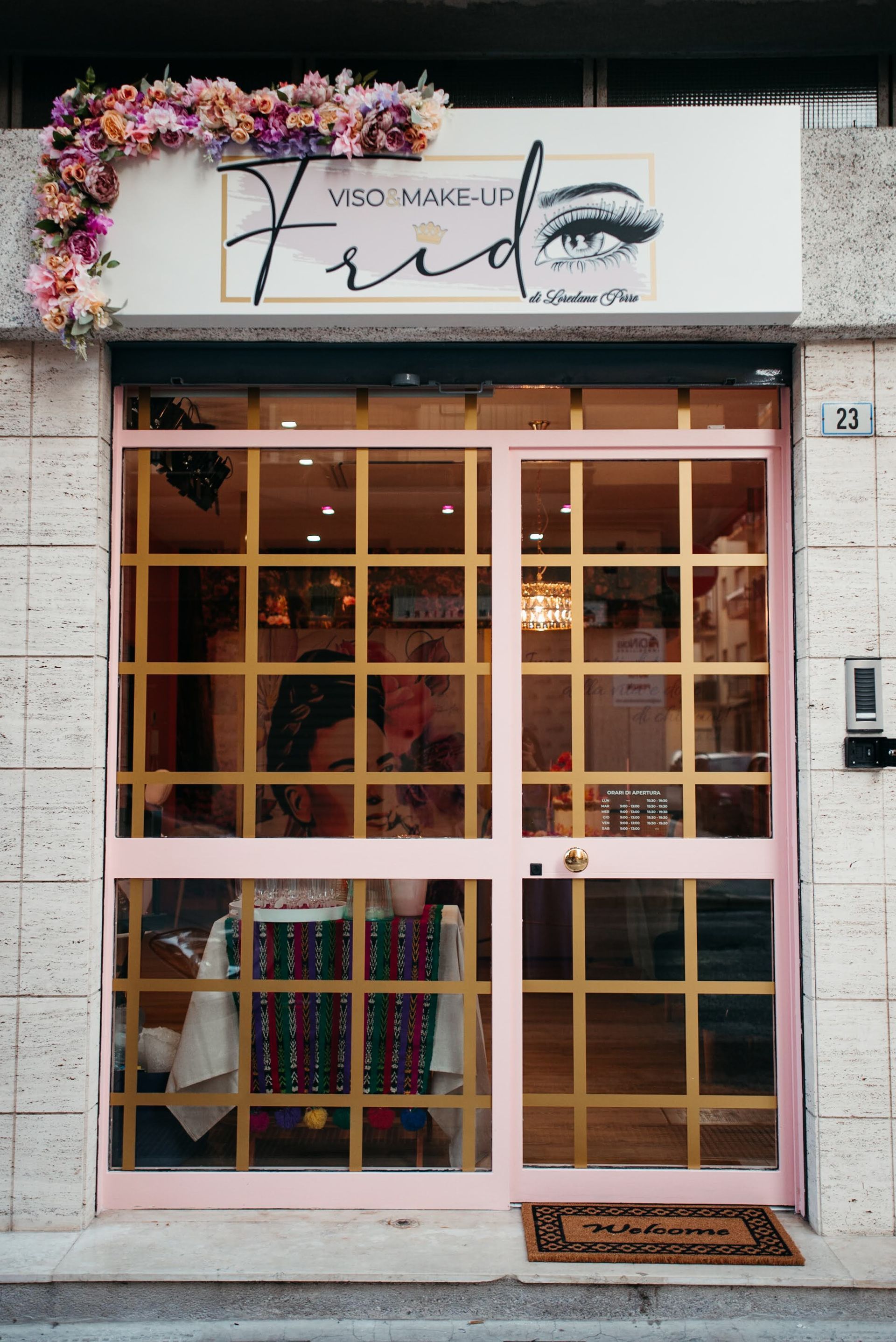 Vetrina con cornice rosa, griglia dorata, decorazioni floreali e insegna: 