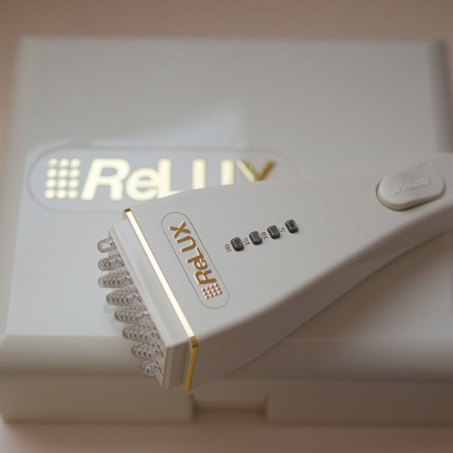 Dispositivo per la fototerapia ReLUV bianco con LED appoggiati sulla sua scatola. Scritta dorata.