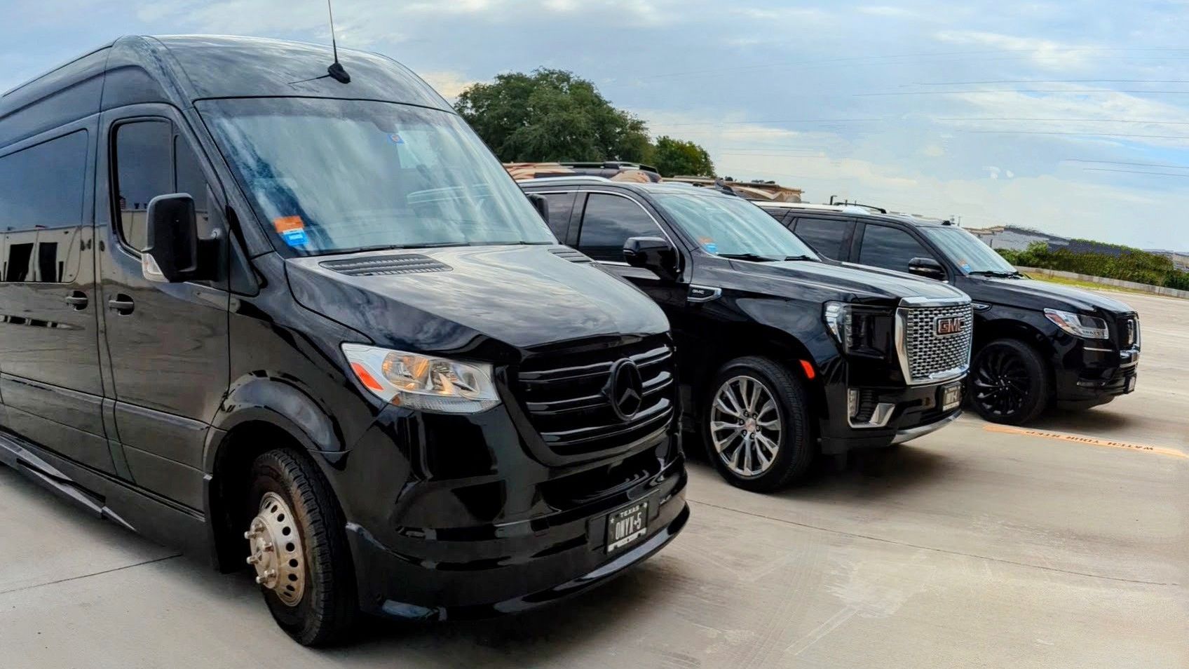A black van and a black suv are parked next to each other on the side of the road.Onyx Black Car Service
