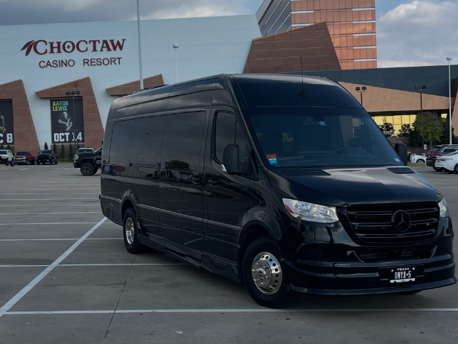 A black van is parked in a parking lot in front of a casino resort.