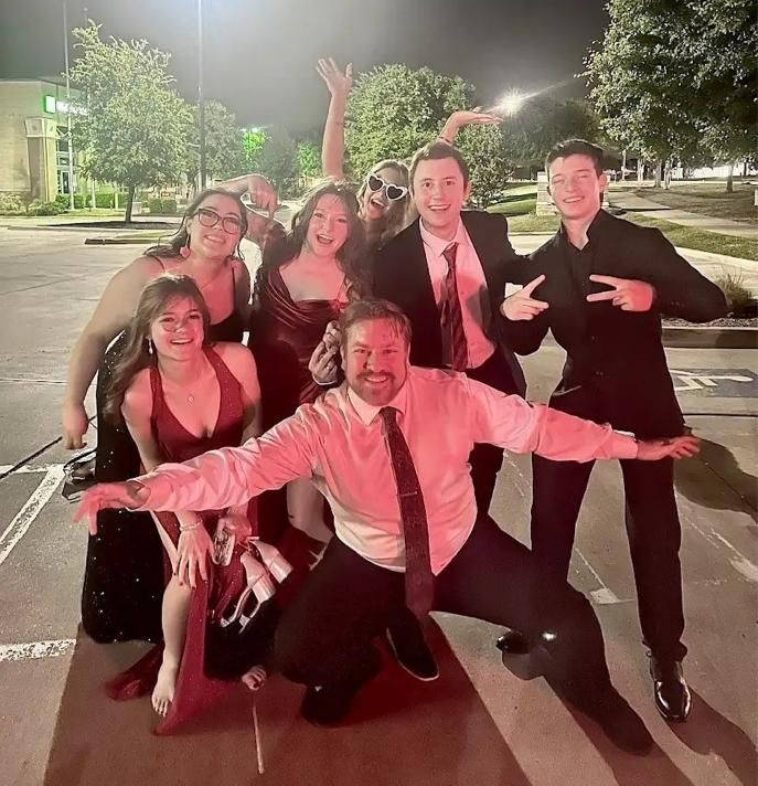 A group of women in dresses are posing for a picture at a prom.