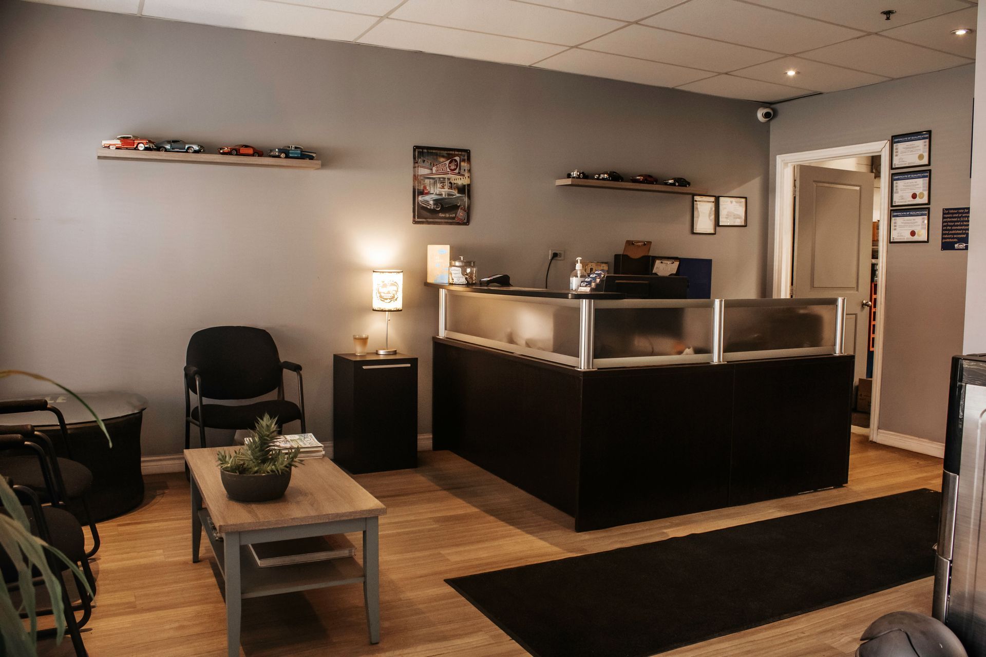A waiting room with a reception desk, chairs, and shelves displaying merchandise.