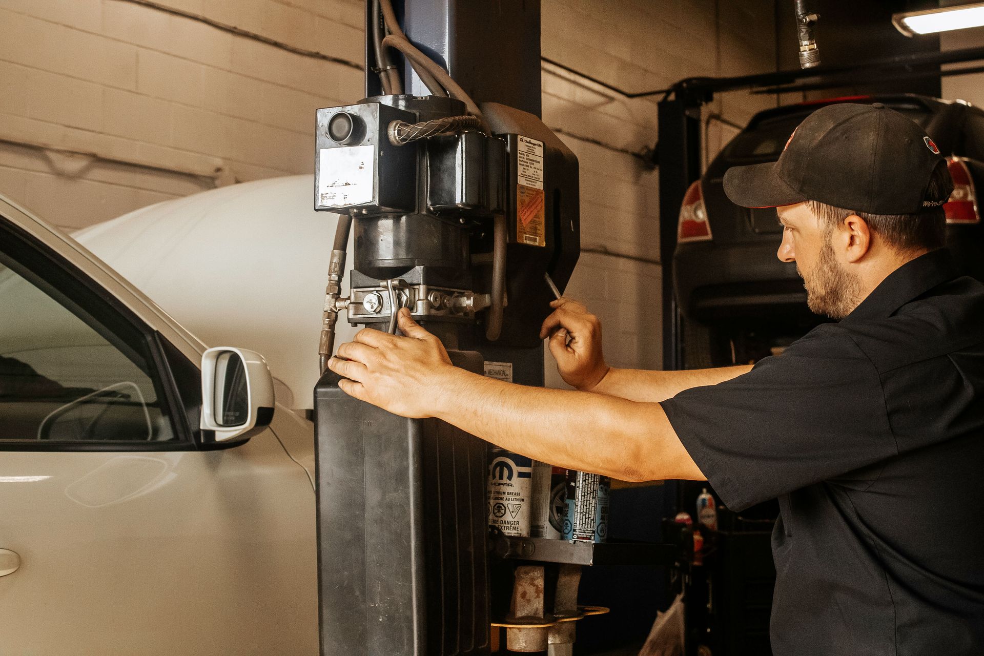 Mechanic working on a car lift in a garage.
