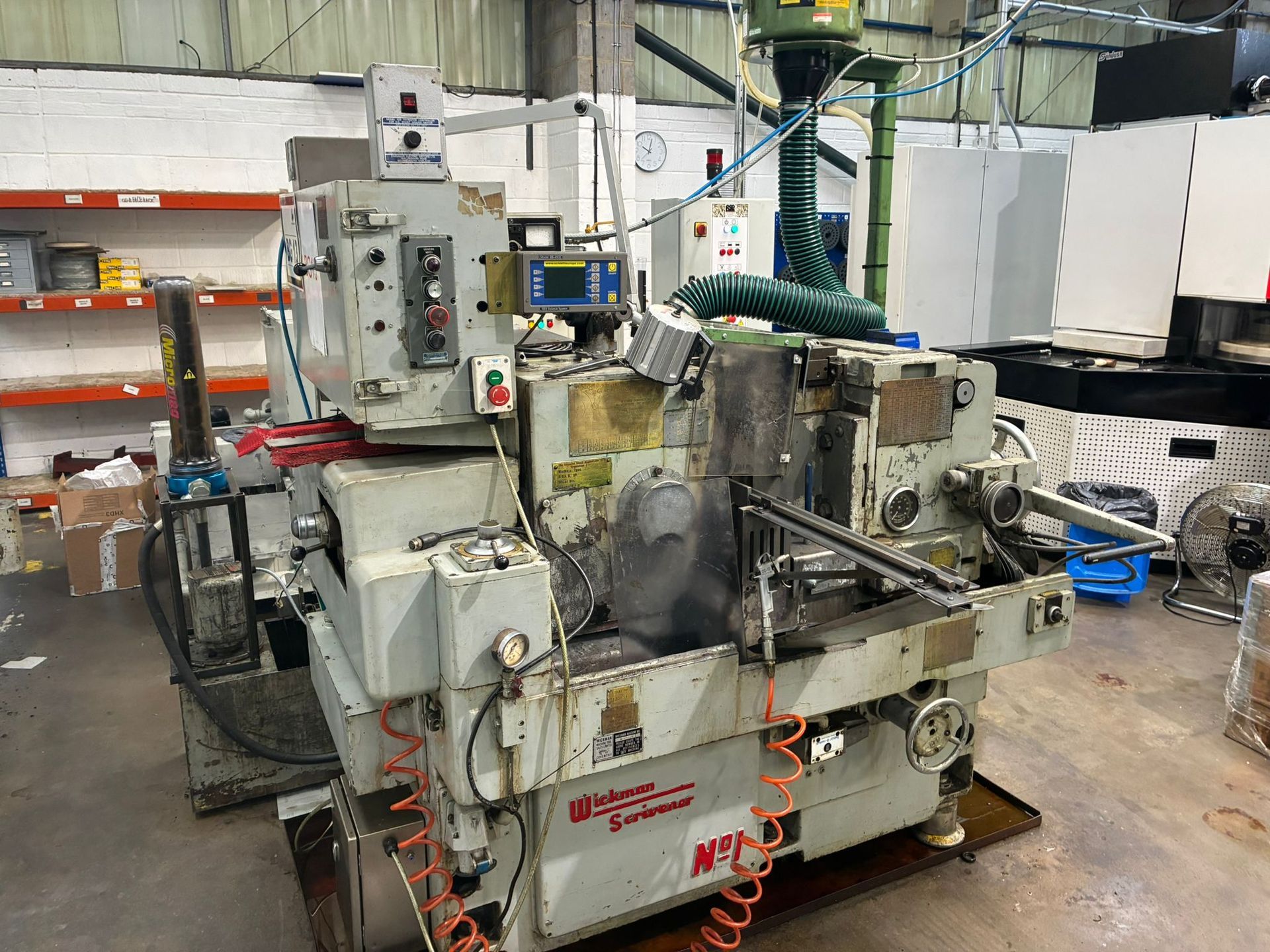 A large machine is sitting in a factory next to a green table.