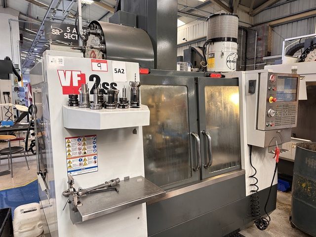 A large machine is sitting in a factory next to a green table.