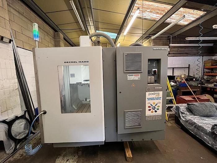 A machine is sitting in a warehouse next to a couch.