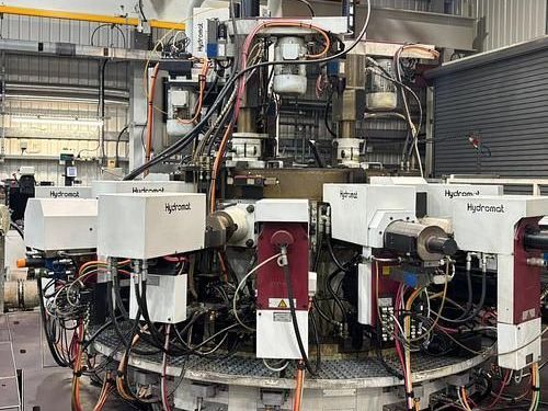 A large machine is sitting in a factory with a lot of wires coming out of it.