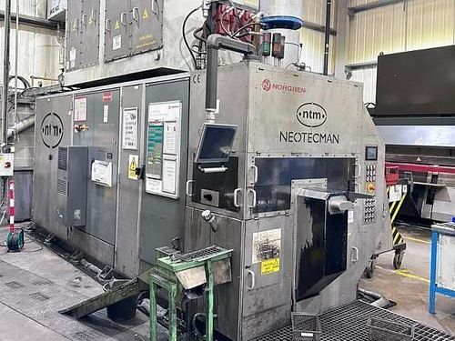 A large machine is sitting in a factory next to a green table.