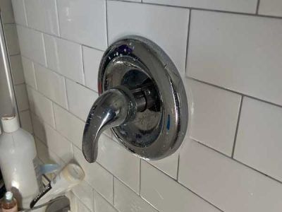 Chrome shower handle on white subway tile.