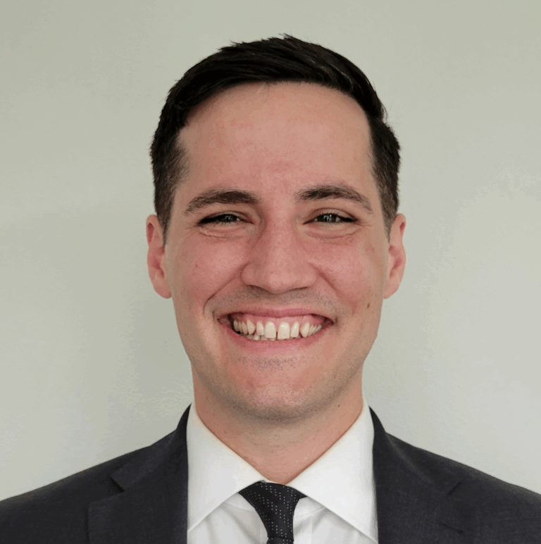 Man in a suit smiling, headshot. White background.