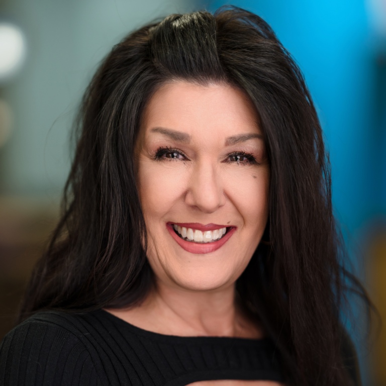 Woman with long dark hair smiles widely; black top.