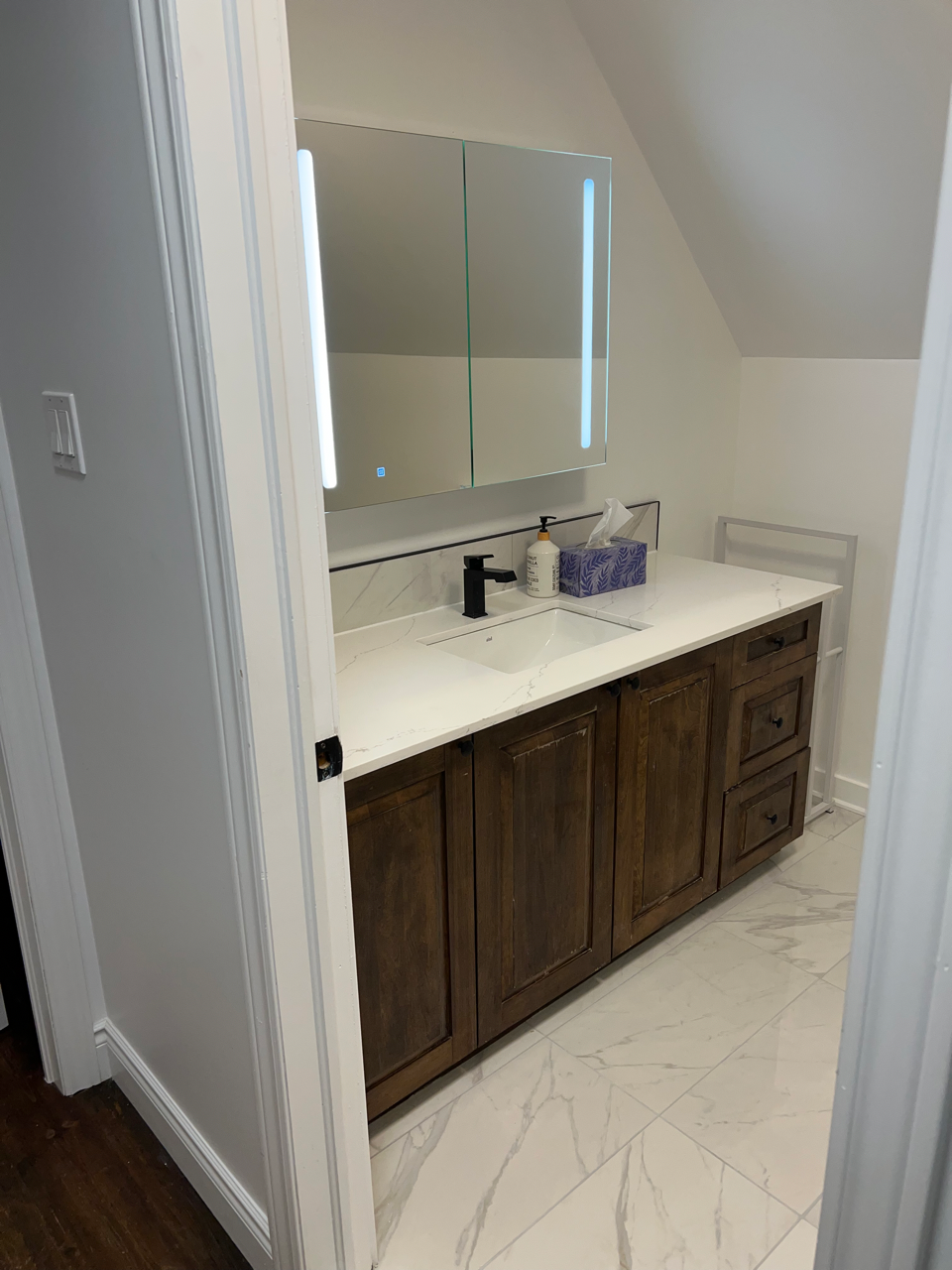 Une salle de bain avec lavabo, miroir et armoires.