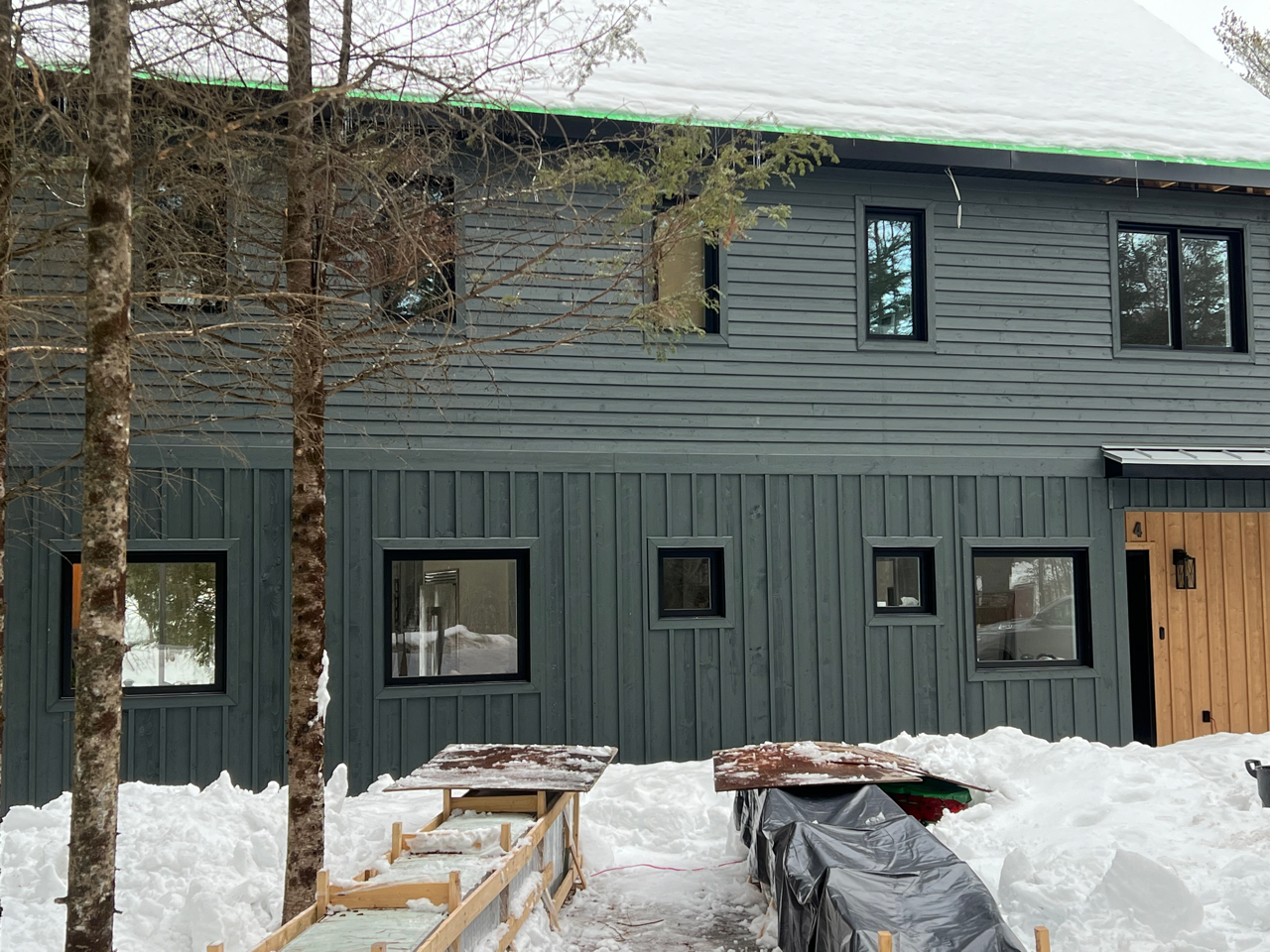 Une grande maison avec beaucoup de fenêtres est recouverte de neige.