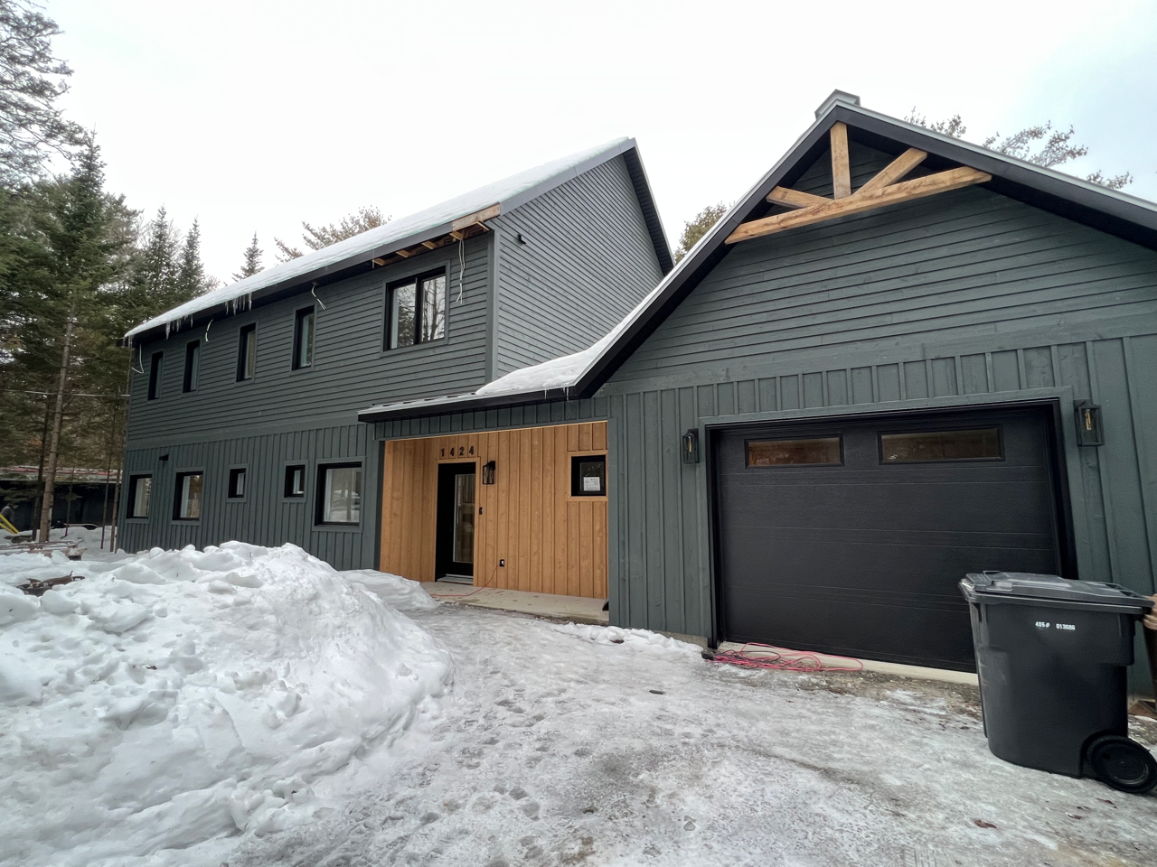 Une grande maison avec un garage est recouverte de neige.