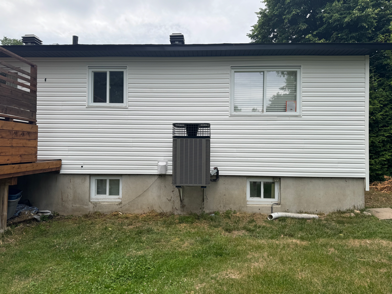 Une maison blanche avec un toit noir et une terrasse dans l'arrière-cour.