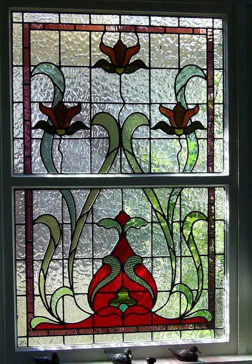 red and green design leadlight with statue birds on a windowsill