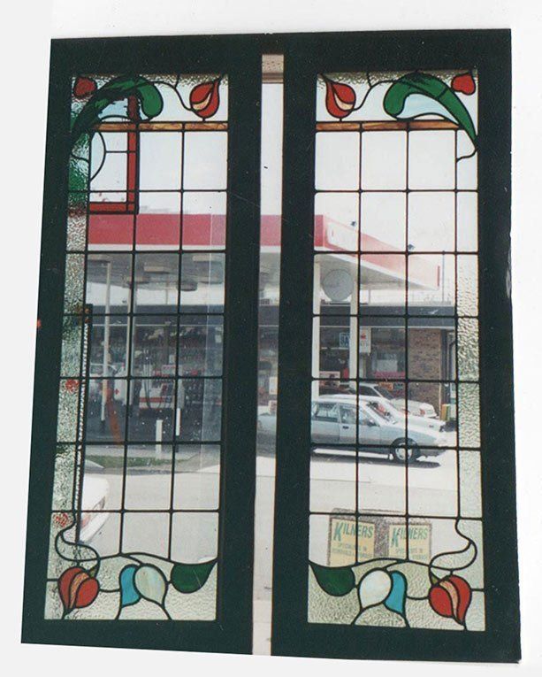 two panel leadlight window with flowers and a business seen through the background