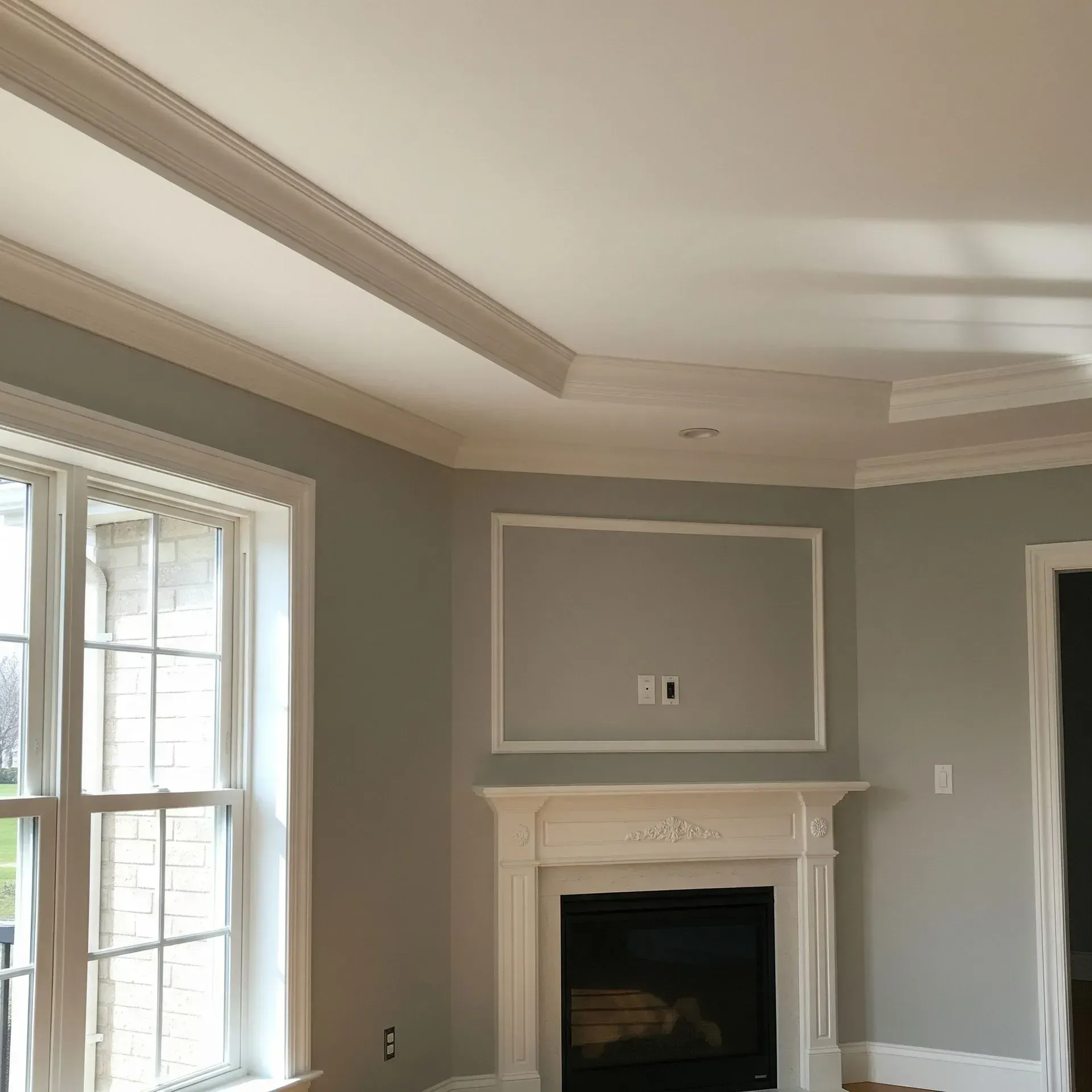 Living room with a fireplace, white trim, grey walls, and coffered ceiling.