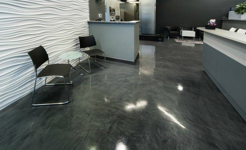 Reception area with wavy white wall, gray floor, counter, chairs.