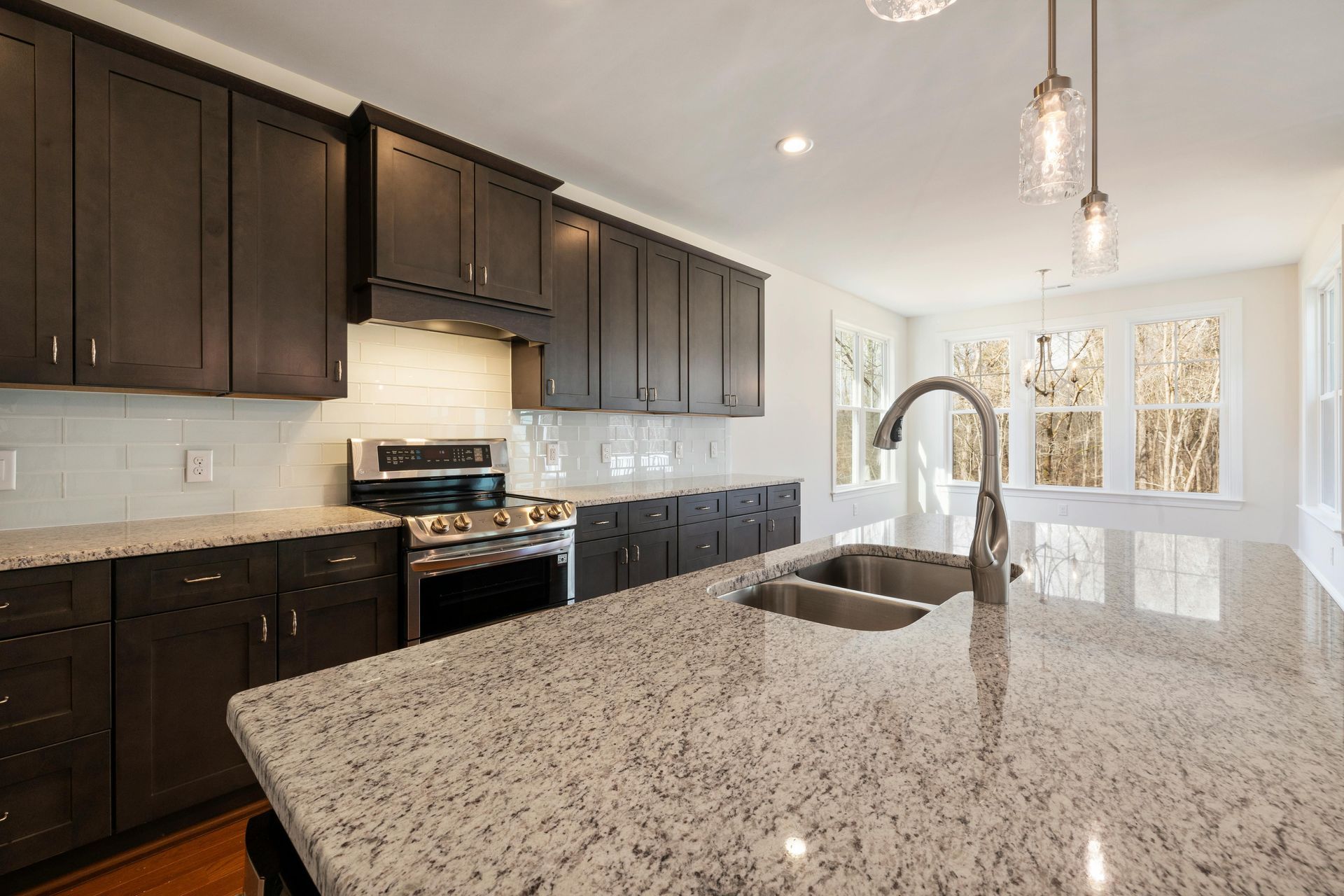 Kitchen with dark cabinets, granite countertop, stainless steel appliances, and sink.