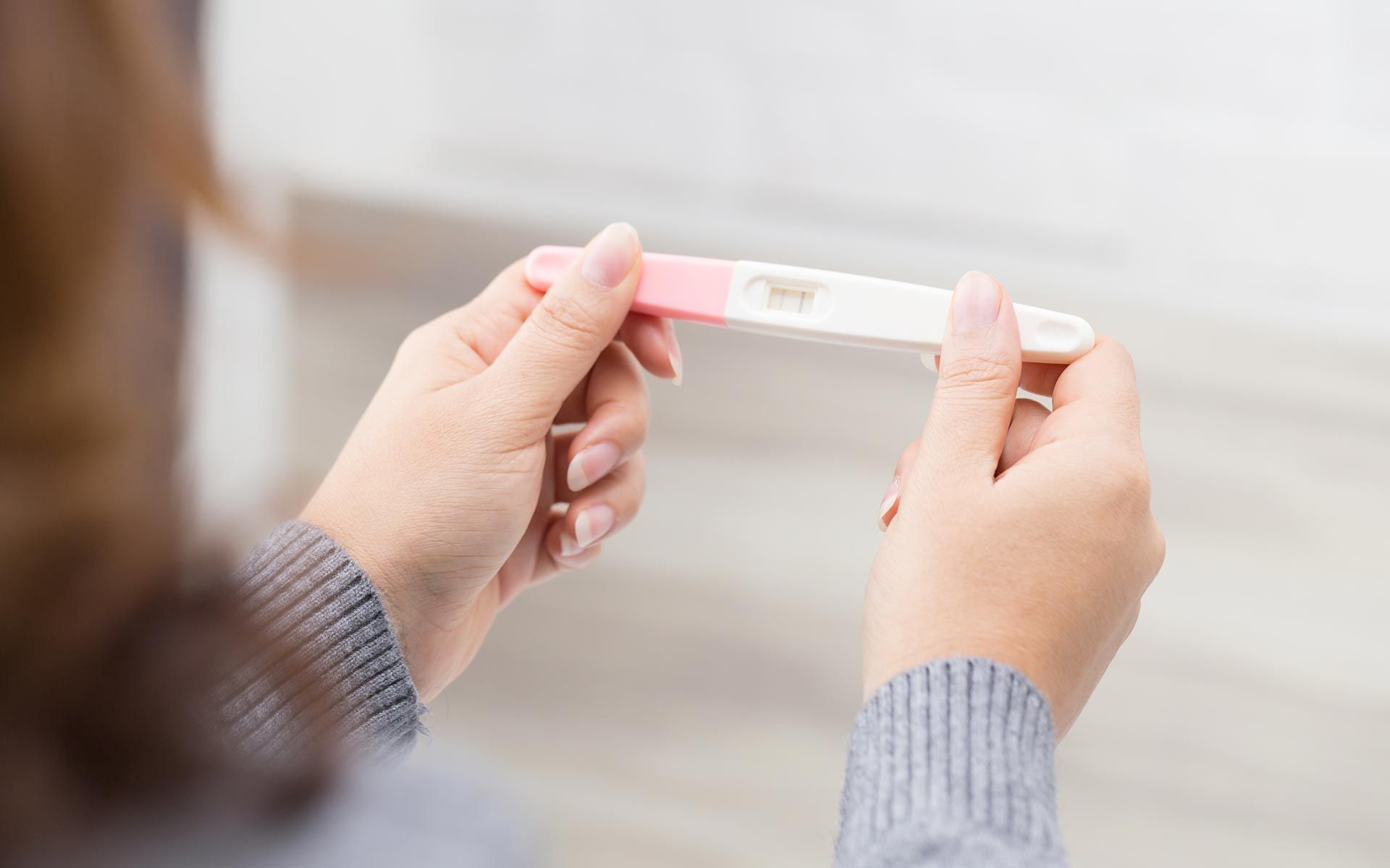 Person holding a home pregnancy test while viewing the result.