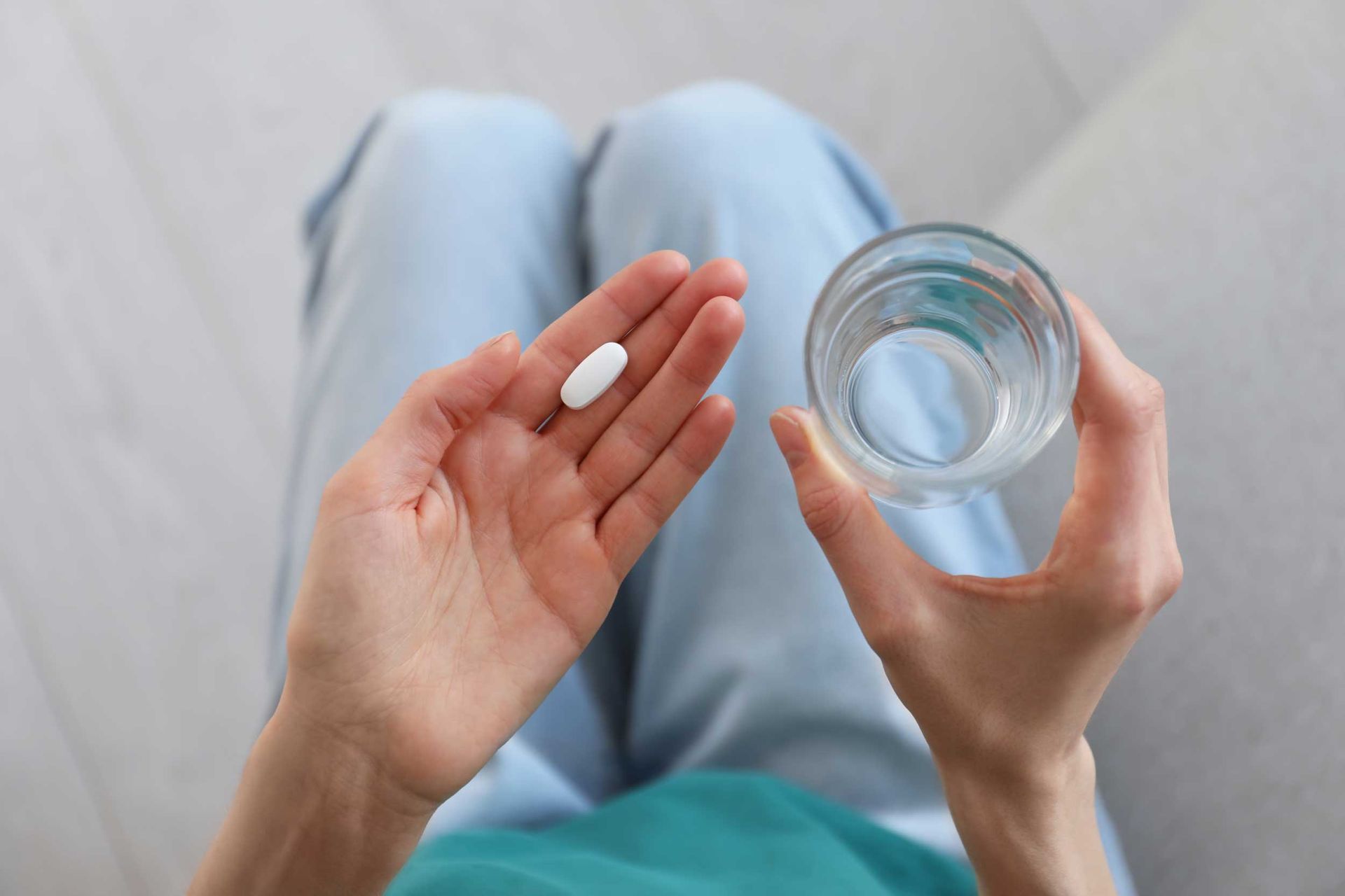 Top view of a young woman with an abortion pill and a glass of water, showcasing abortion services.
