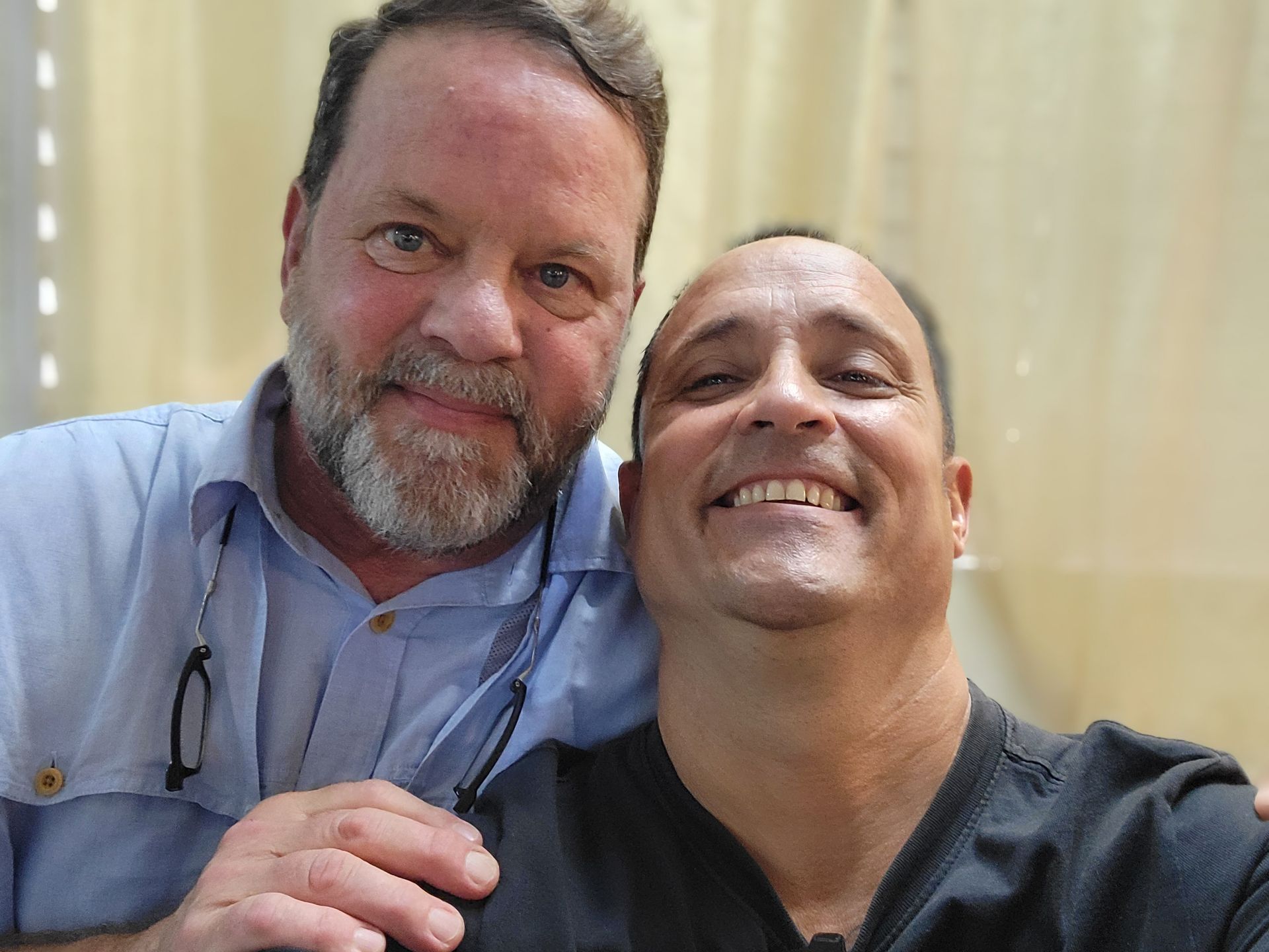 Two men are posing for a picture together and smiling for the camera.