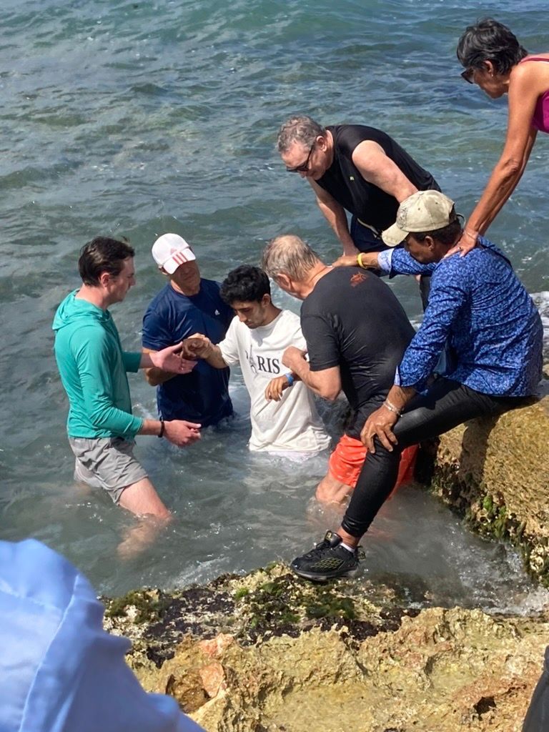 A group of men are standing on rocks in the water.