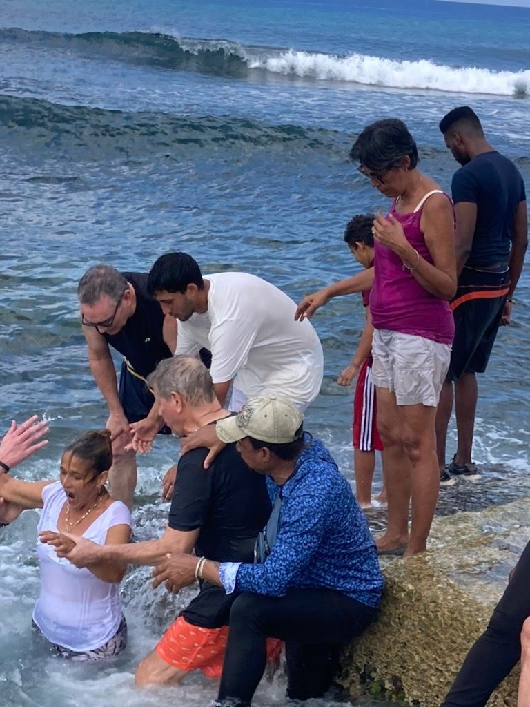 A group of people are standing on a rock near the ocean.
