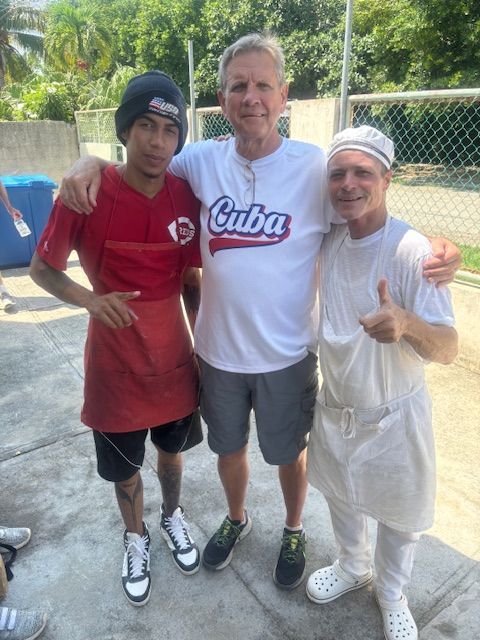 A man wearing a cuba shirt is posing with two other men