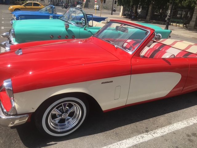 A red and white convertible is parked in a parking lot