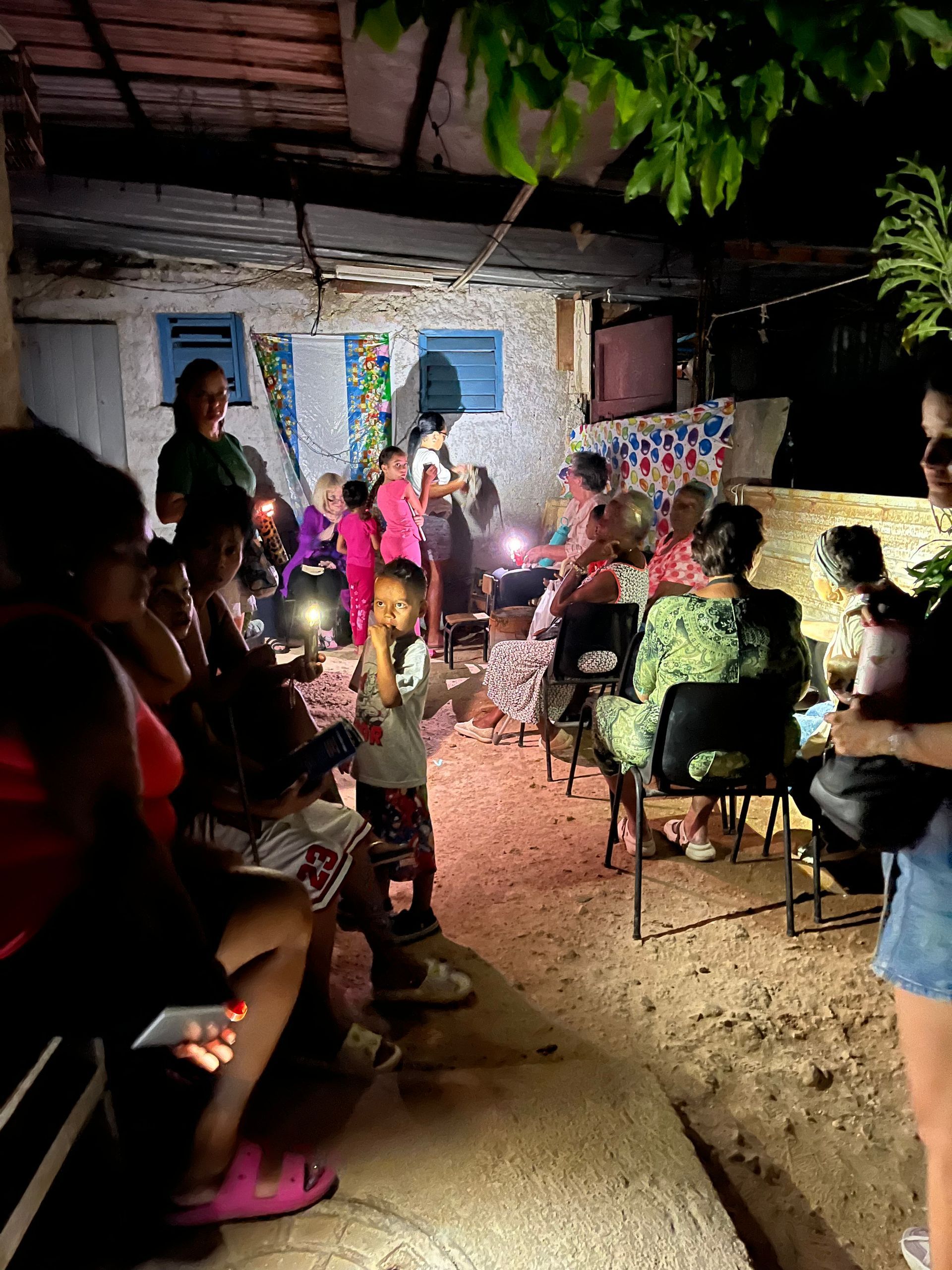 A group of people are sitting in chairs in a room at night.