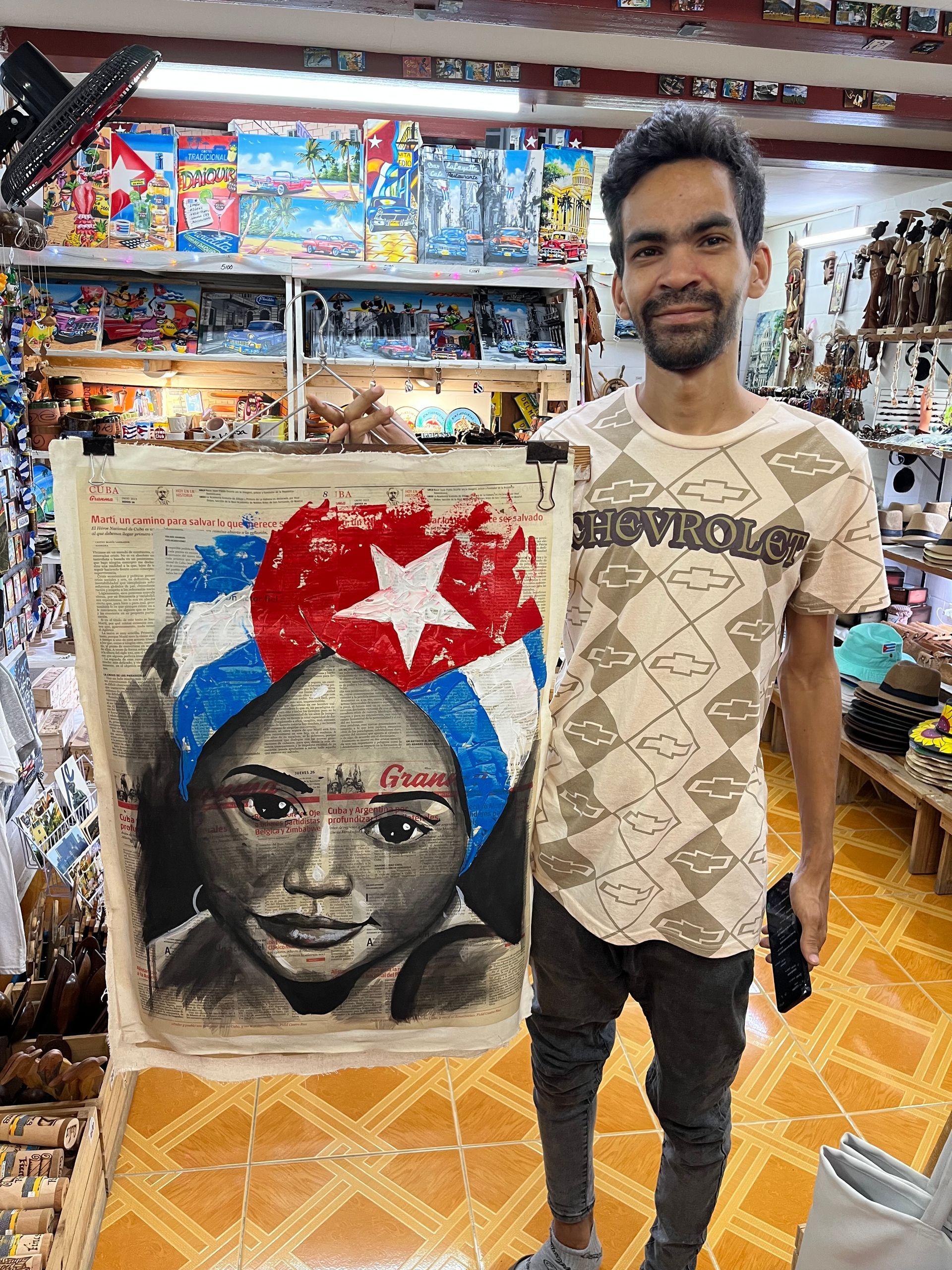 A man is holding a painting of a woman in a turban in a store.