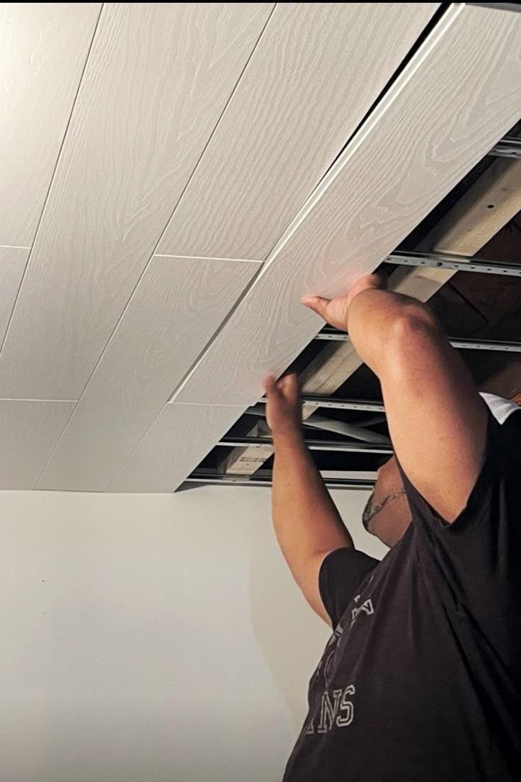 Worker installing a ceiling in a finished basement