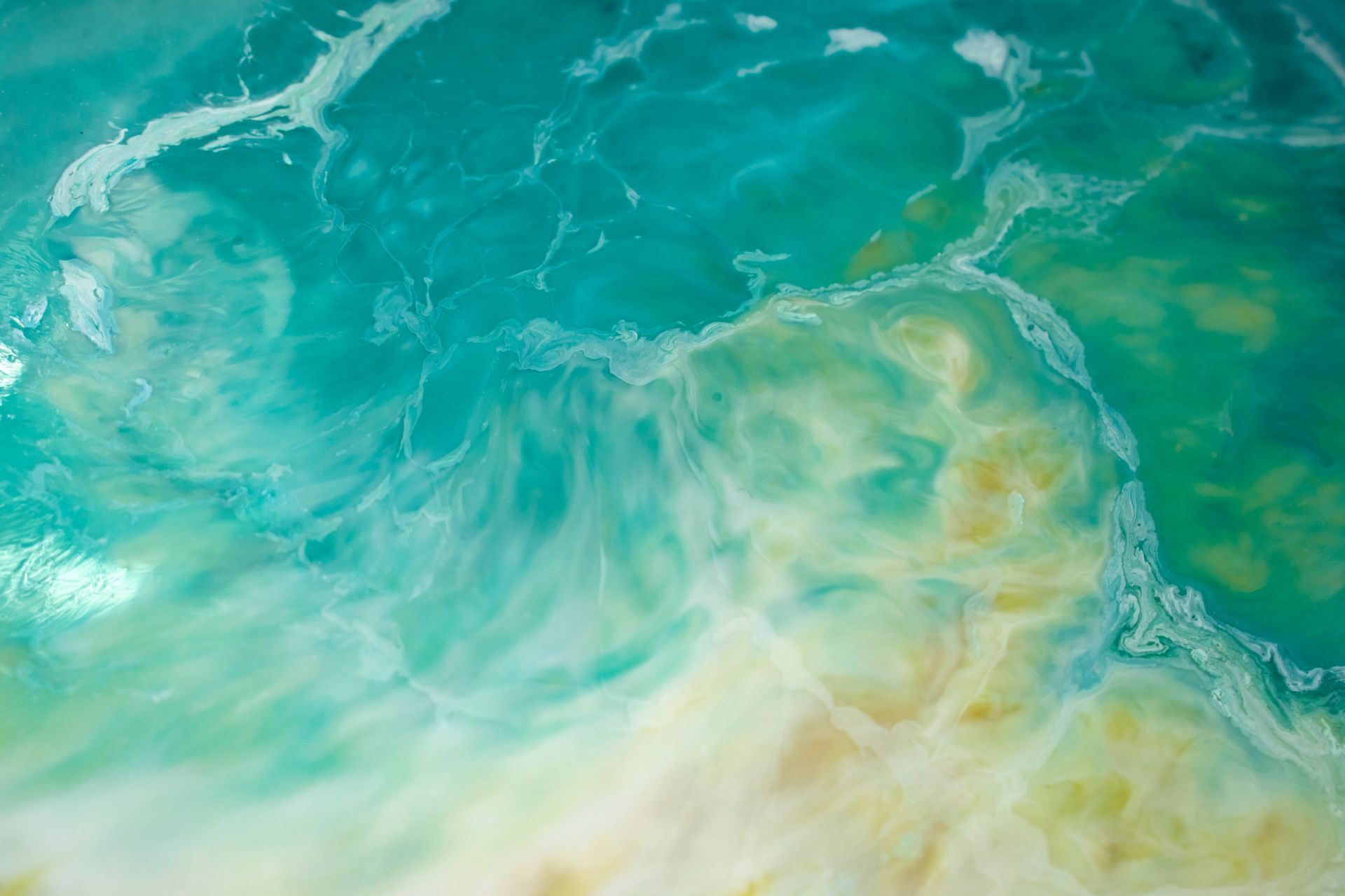 Vagues de l'océan dans des tons turquoise, blanc et or, ressemblant à une vue aérienne d'un littoral.