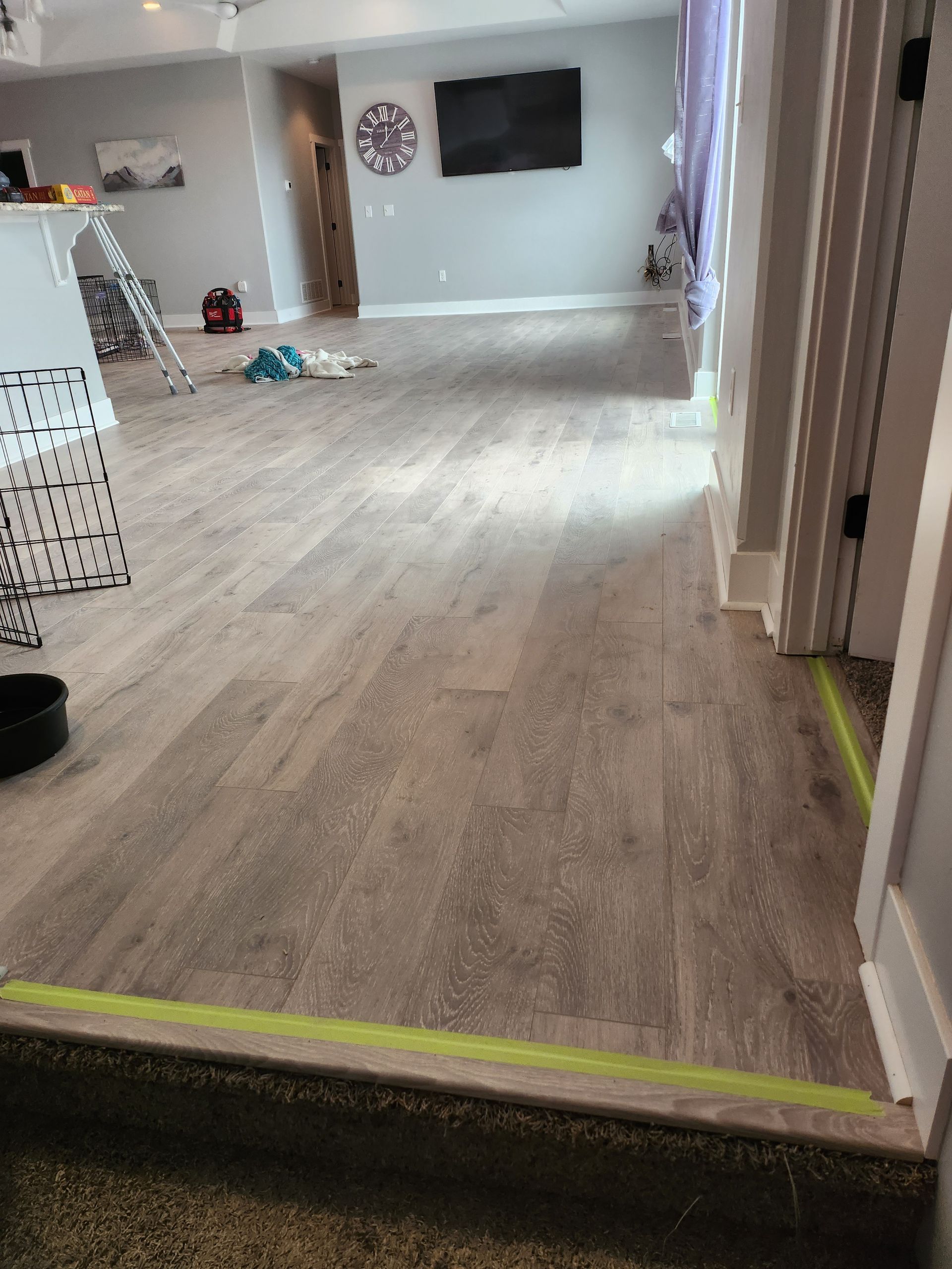 A living room with hardwood floors and a yellow tape on the floor.