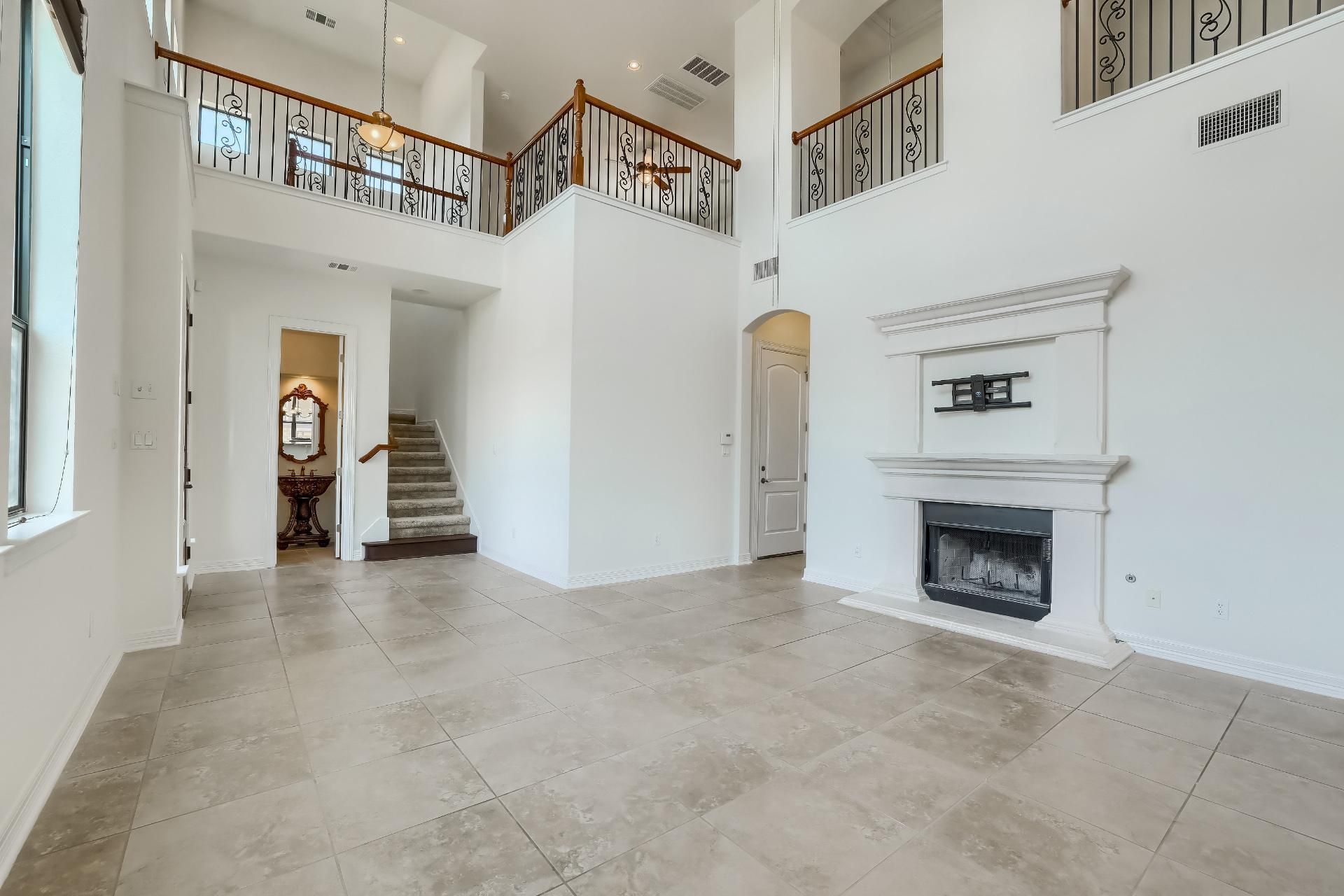 Living room with a double-height ceiling, floor-to-ceiling windows, and an elegant fireplace