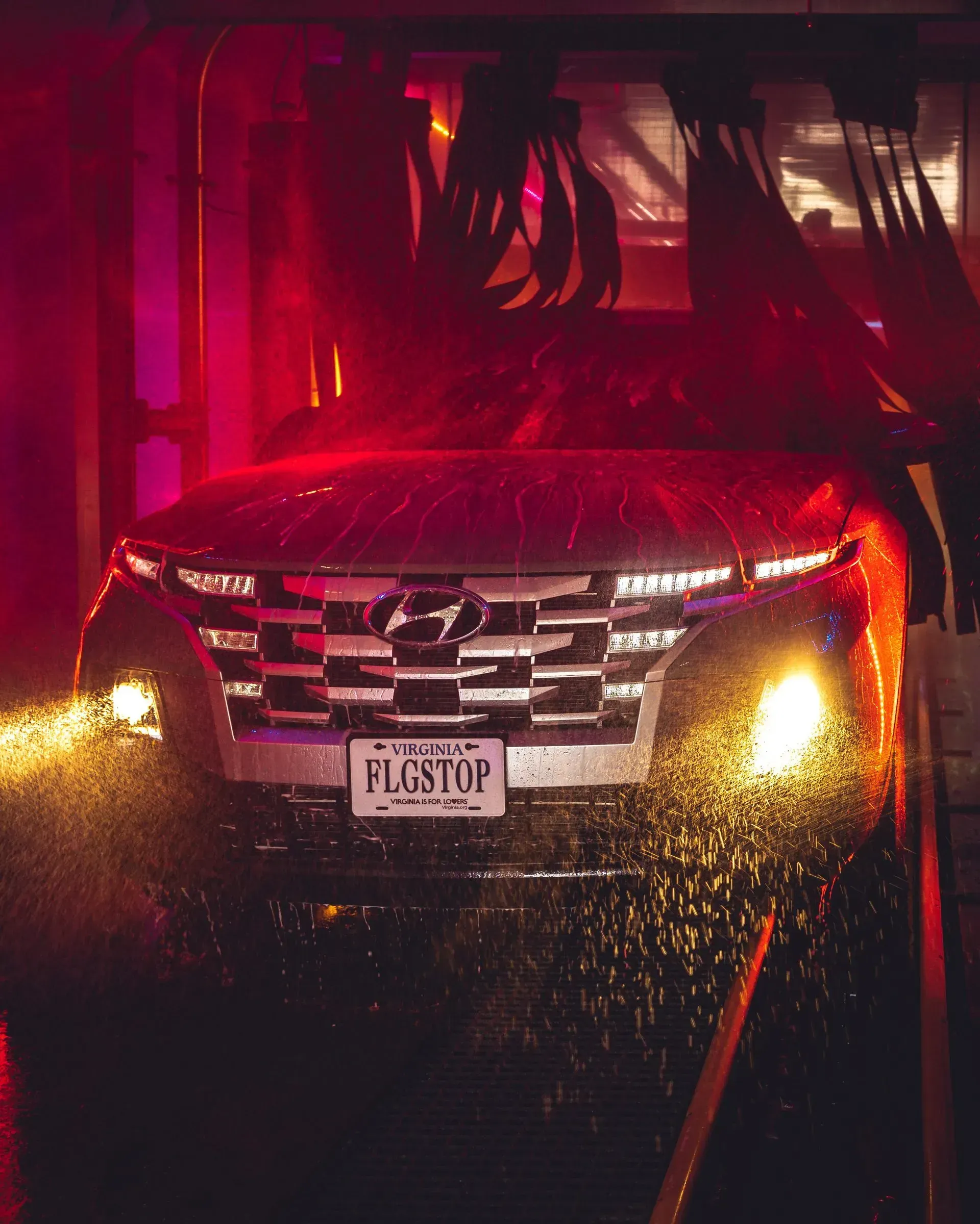A car with a license plate that says pigstop is being washed in a car wash.
