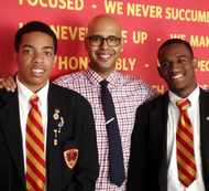 Three men are posing for a picture in front of a sign that says 