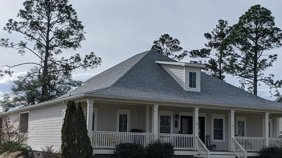 A white house with a porch and trees in the background