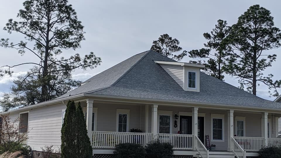 A white house with a porch and trees in the background