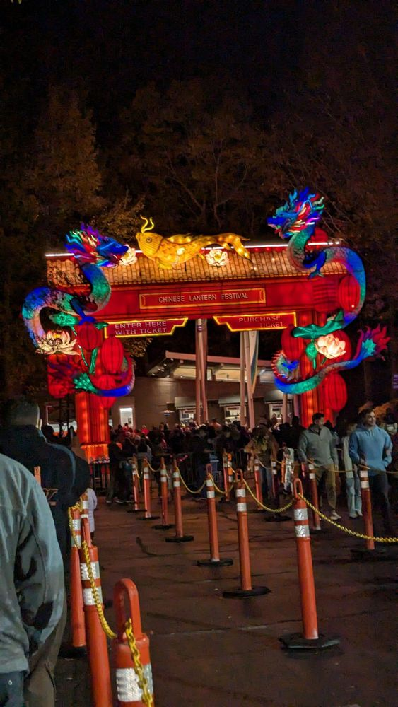 A group of people are standing in front of a gate with a dragon on it.