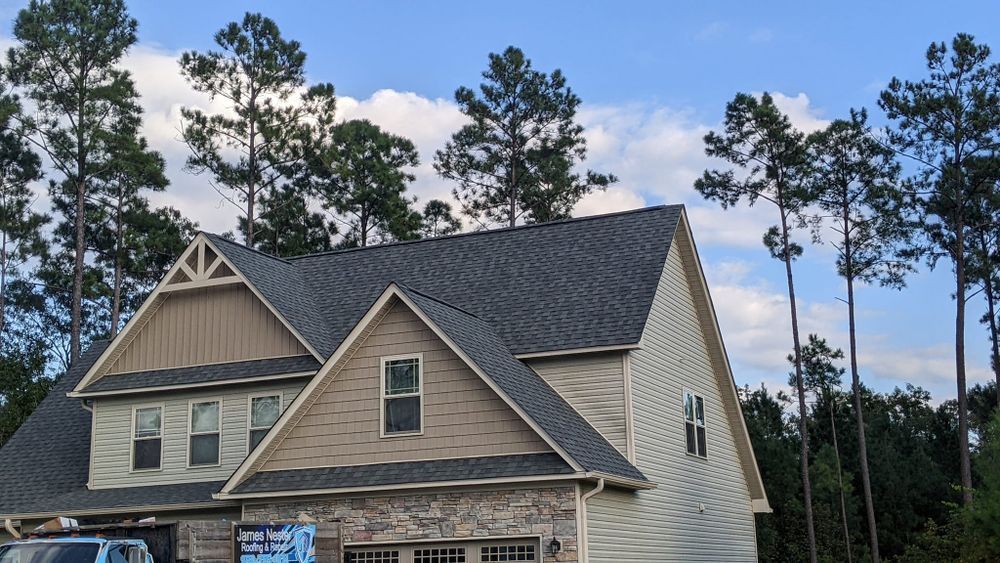 A large house with a gray roof is surrounded by trees.