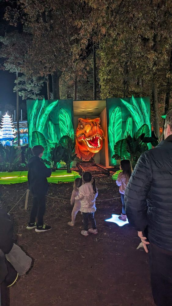 A group of people are standing in front of a large screen with a tiger on it.